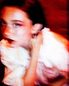 a blurry photo of a woman in a white dress with her hand on her shoulder