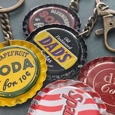 several soda bottle caps are hanging on a metal keychain that says dad's