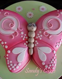 a cake shaped like a pink butterfly with white swirls on it's wings