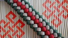 a close up of a woven object on a tablecloth with red, white and green beads