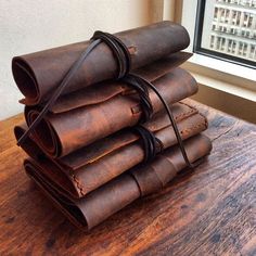 a stack of old books sitting on top of a wooden table next to a window