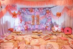 a pink and gold themed birthday party with balloons, streamers and pillows on the floor