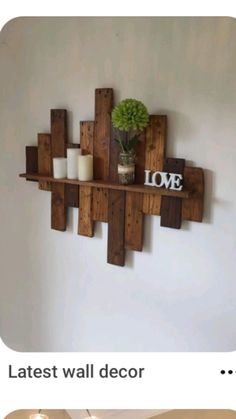 a wooden shelf with some candles and a vase on top of it that says love