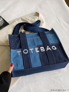 a handbag with the word tote bag printed on it, sitting on top of a bed