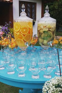 there are many glasses on the table with fruit and drinks in them, all lined up