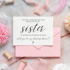 a pink envelope with the words sister on it next to some flowers and other items