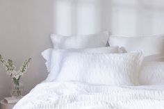 a bed with white sheets and pillows in a room