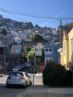 a car parked on the side of a road next to a stop sign and buildings