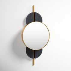 an oval mirror mounted to the side of a wall next to a black and gold frame