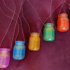 colorful jars are hanging from strings on a purple background