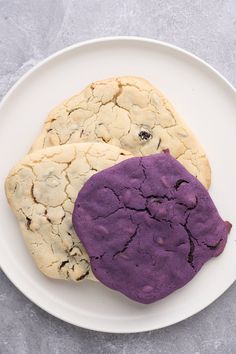 two cookies with purple frosting on a white plate