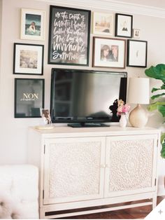 a white entertainment center with pictures on the wall