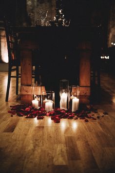 candles and rose petals on the floor in front of a table