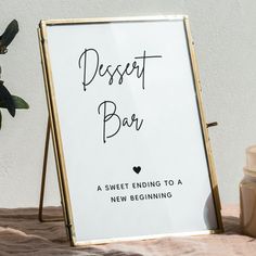 a dessert bar sign sitting on top of a table next to a potted plant