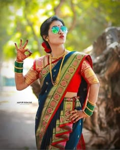 a woman in a colorful sari holding her hand up to the sky while wearing sunglasses