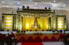 an elaborate stage set up for a wedding ceremony with flowers and greenery on the floor