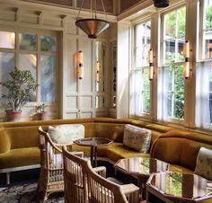 a living room filled with lots of furniture next to large windows and potted plants