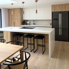 a kitchen with white counter tops and black chairs