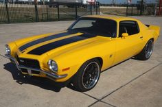 a yellow muscle car parked in a parking lot