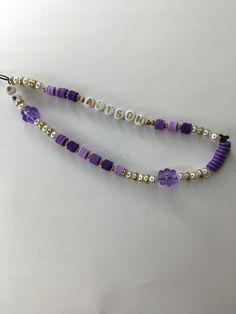 two purple and white beaded necklaces sitting on top of a table