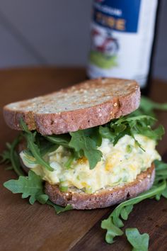 there is a sandwich with lettuce and eggs on it next to a bottle of beer