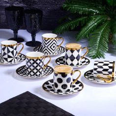 coffee cups and saucers decorated with black and white geometric designs, on a table