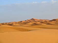 the desert is covered in sand dunes and clouds