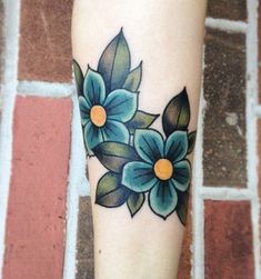 a woman's leg with blue flowers on it and green leaves around the legs