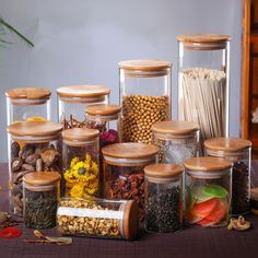 the jars are filled with different types of spices and nuts, including dried flowers, corn kernels, and other edible items