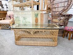 a wicker coffee table with glass top in front of some chairs and other furniture