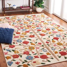 a white rug with multicolored flowers and leaves on it in a living room