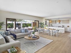 a living room filled with furniture next to a kitchen and dining room table on top of a hard wood floor