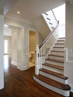 a staircase in a house with hardwood floors and white railings