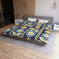 a bed with a blue and yellow bedspread on it in a bedroom next to a wooden floor