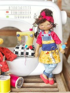 two dolls are sitting next to a sewing machine