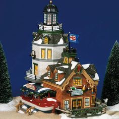 a toy house with cars and trees in front of it on a snow covered ground