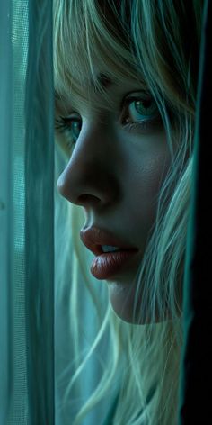 a woman with blue eyes looking out the window