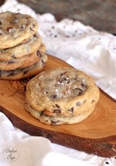 three chocolate chip cookies sitting on top of a wooden board