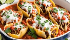 mexican stuffed shells in a blue dish with sour cream and garnish on top