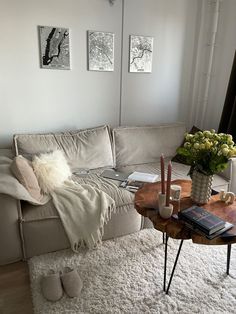 a living room with a couch, coffee table and books on the floor in front of it