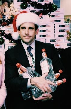 a man in a santa hat holding two bottles