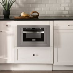 a kitchen with white cabinets and black counter tops, an oven built into the wall