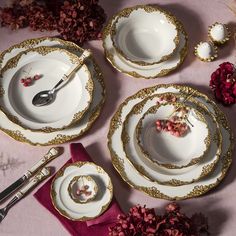 a table topped with plates and silverware next to flowers