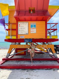 a woman standing in front of a lifeguard tower on the beach