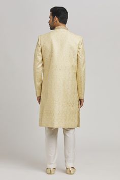 Ivory and golden sherwani with floral frame embroidery. Paired with an inner kurta and churidar. - Aza Fashions Gold Straight Kurta Churidar For Reception, Gold Churidar With Straight Kurta For Reception, Traditional Gold Raw Silk Wear With Naqshi, Gold Jamawar Sets With Naqshi Details, Gold Jamawar Sets For Reception, Gold Straight Kurta For Reception, Gold Naqshi Unstitched Straight Kurta Suit, Festival Gold Unstitched Suit With Naqshi Detail, Gold Unstitched Suit With Naqshi Embroidery