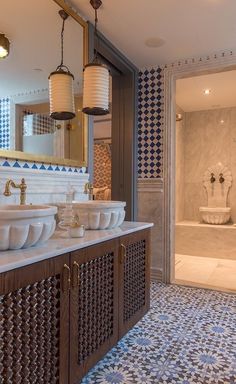 a bathroom with blue and white tiles on the walls, two sinks and a tub