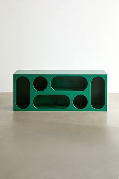 a green box with holes in it sitting on the floor next to a white wall