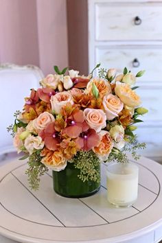 a vase filled with flowers sitting on top of a white table next to a candle