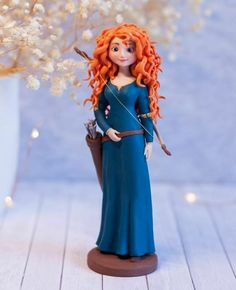 a doll with red hair holding a wand and wearing a blue dress