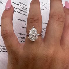 a woman's hand with a ring on it and a sheet of paper in the background